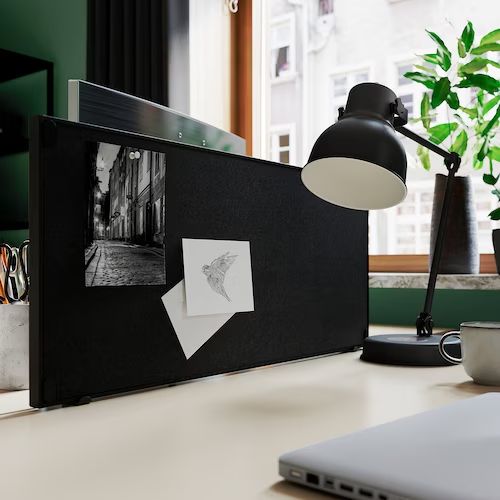 an office desk with a laptop, lamp and pictures on the wall next to it