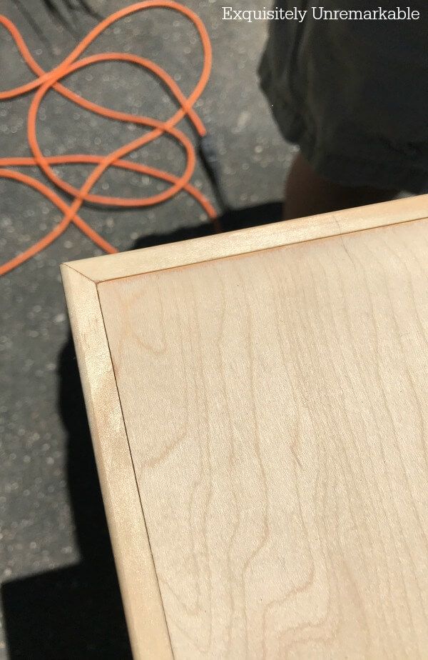 a person standing next to a wooden box with an orange cord on top of it