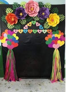 a black backdrop with paper flowers and tassels on the sides, along with other decorations