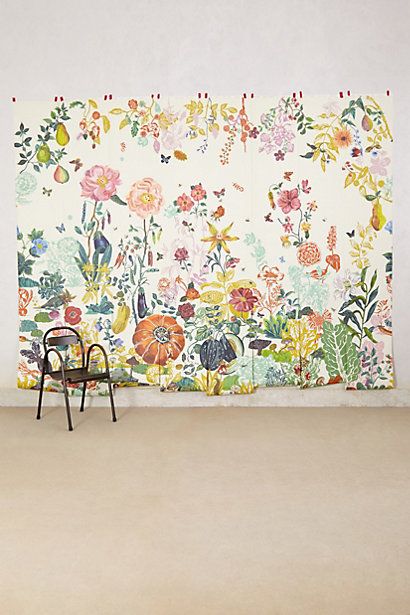 a chair sitting in front of a wall with flowers on it's back side