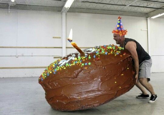 a man carrying a giant piece of cake with candles on it