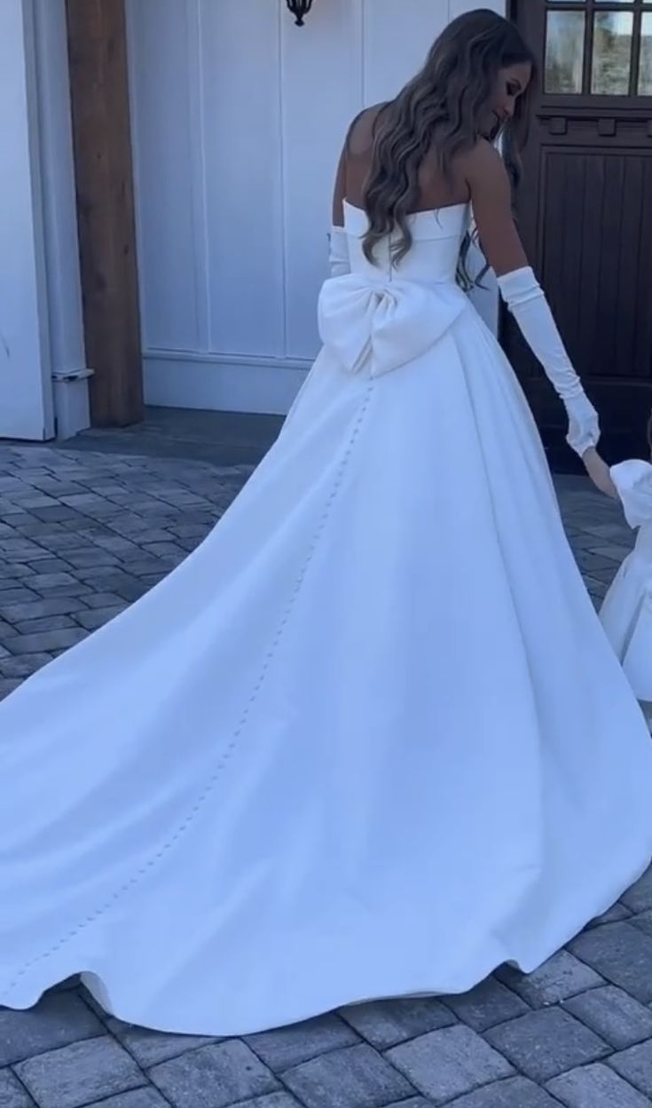 a woman in a white wedding dress holding the hand of a child