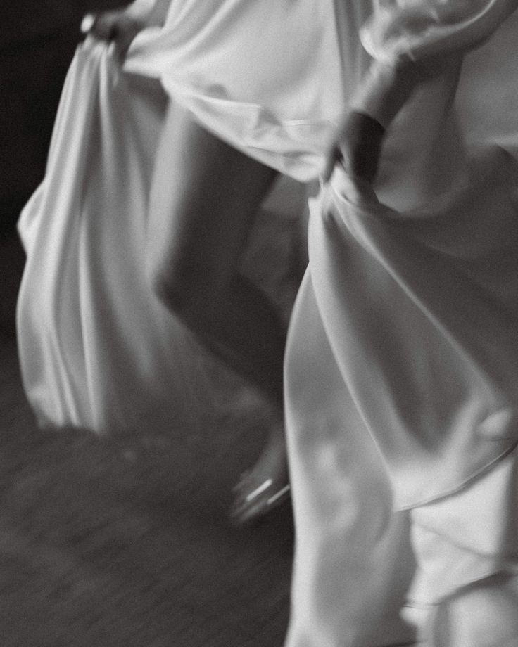 two women in white dresses are dancing on the floor