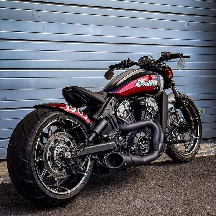 a red and black motorcycle parked in front of a garage door