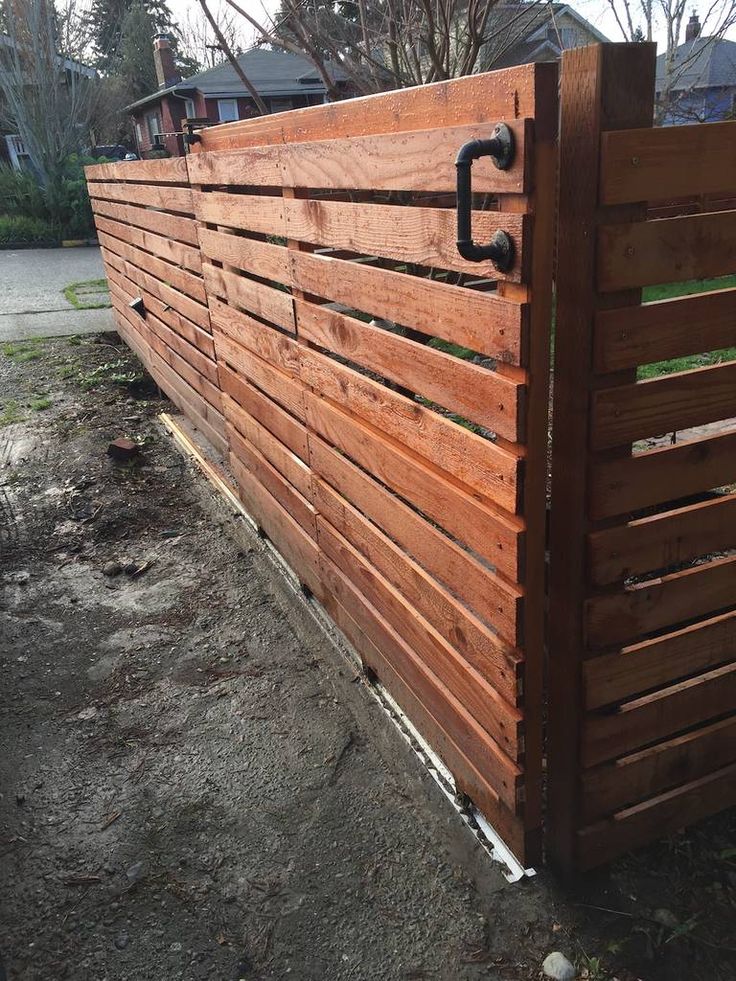 a wooden fence with an iron handle on the top and bottom part, in front of a house