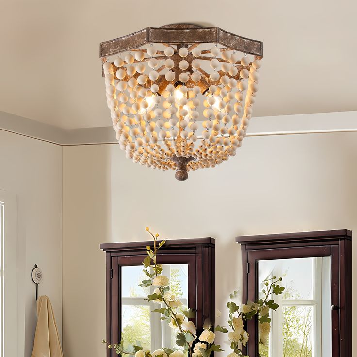 a chandelier hanging from the ceiling in a room with two mirrors and flowers