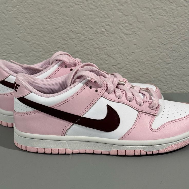 The Nike Dunk Low Pink Red White Gs Features A White Leather Upper Complemented By Pink Overlays And A Deep Red, Purple-Like Shade Marking The Swoosh. The Pink Continues To The Mudguard, Lacing System, And Heel, While Underneath, The Nike Dunk Keeps Its Classic Color Blocking With A White Midsole And A Pink Outsole And Treading. Pink Sneakers For Streetwear With Laces, Sporty Pink Sneakers With Rubber Sole, Pink Custom Sneakers With Gum Sole For Streetwear, Sporty Custom Pink Sneakers With Rubber Sole, Pink Gum Sole Sneakers For Streetwear, Pink Low-top Sneakers With Boost Midsole, Sporty Pink Custom Sneakers With Gum Sole, Sporty Custom Pink Sneakers With Gum Sole, Pink Custom Sneakers With Gum Sole For Sports