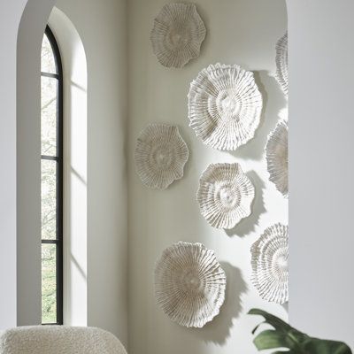 a white chair sitting in front of a window next to a wall with plates on it