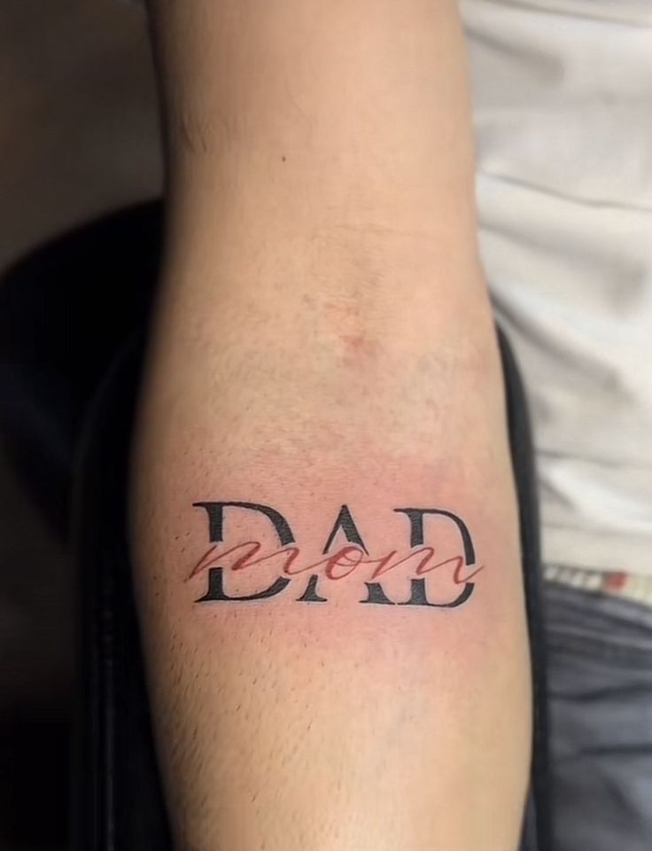 a man's arm with the word dad tattooed on it, in red ink