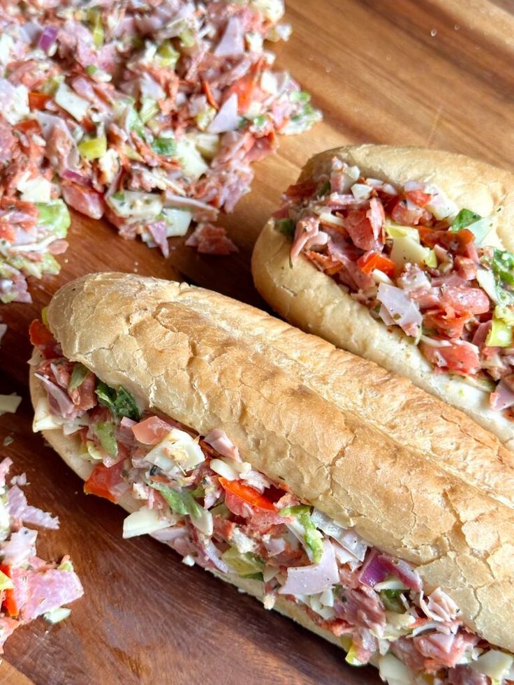 two sub sandwiches cut in half on a cutting board