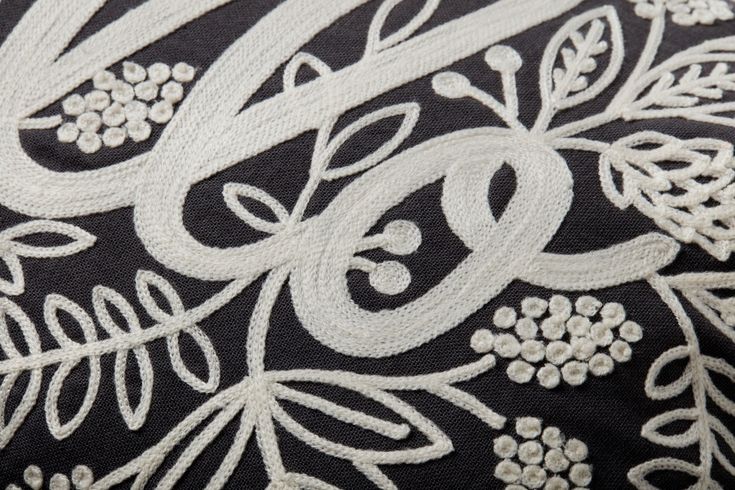 an embroidered black and white pillow with flowers on it