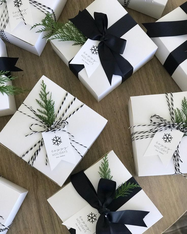 several wrapped gift boxes with black ribbons and pine branches on them, all tied together