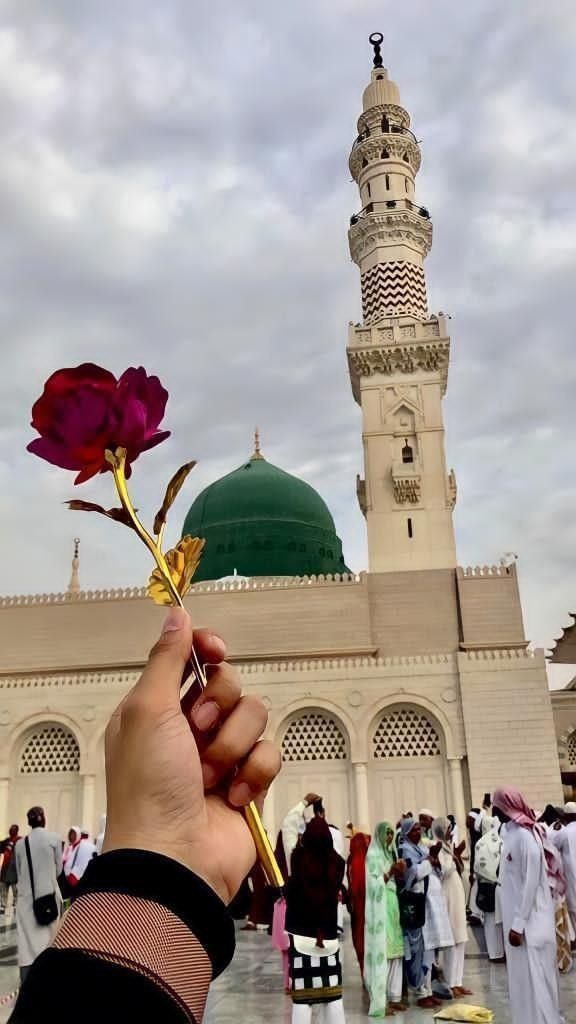 a person holding a flower in front of a building with a green dome on top