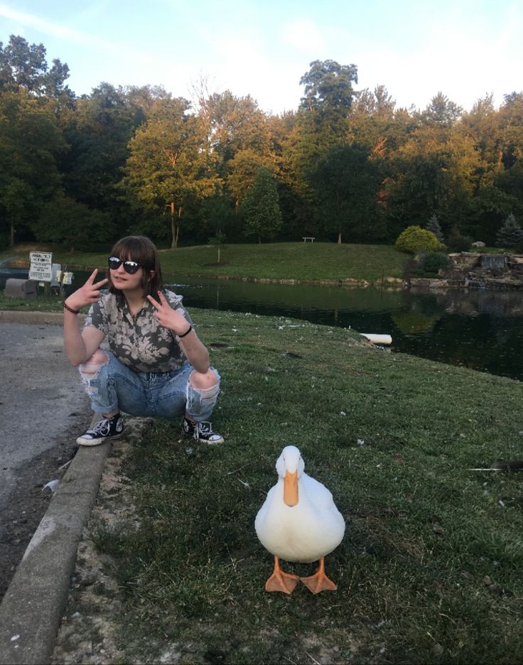 a woman kneeling down next to a duck