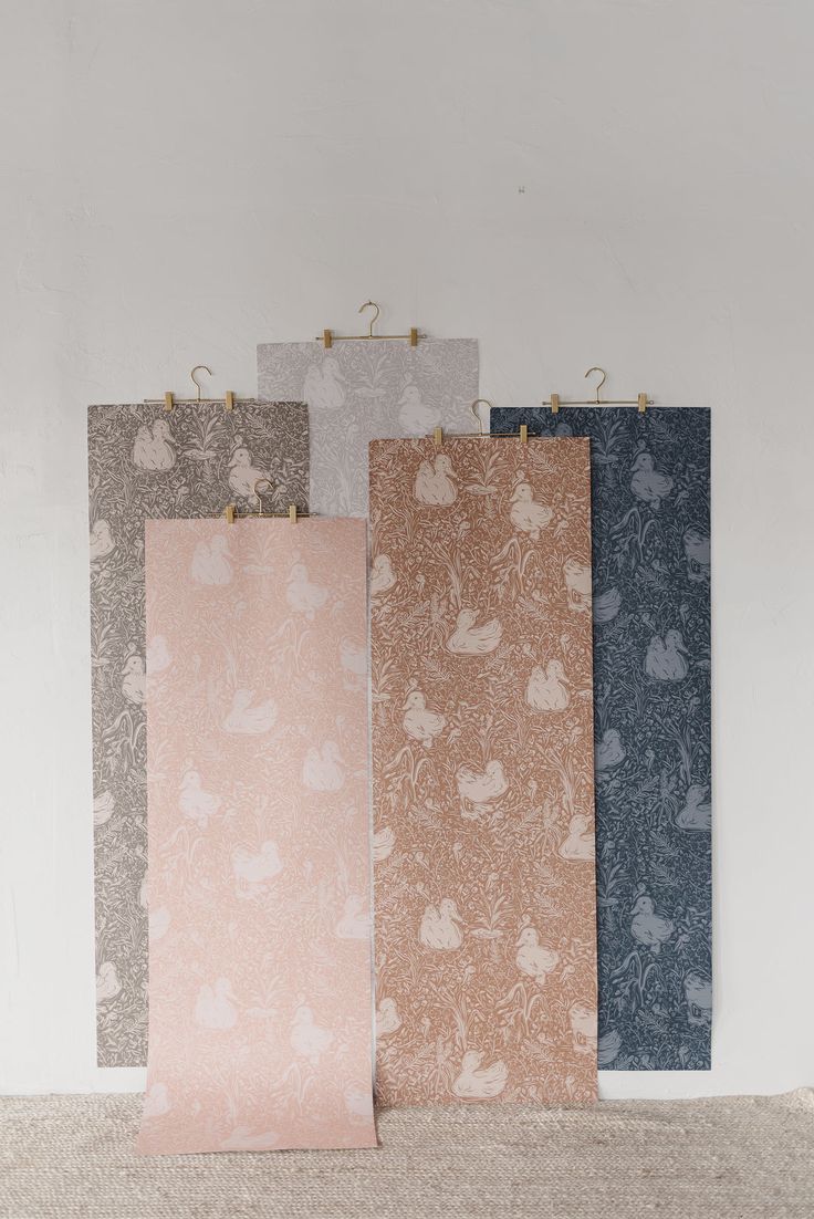 four different colored paper bags hanging from hooks on a white wall, each with an animal pattern