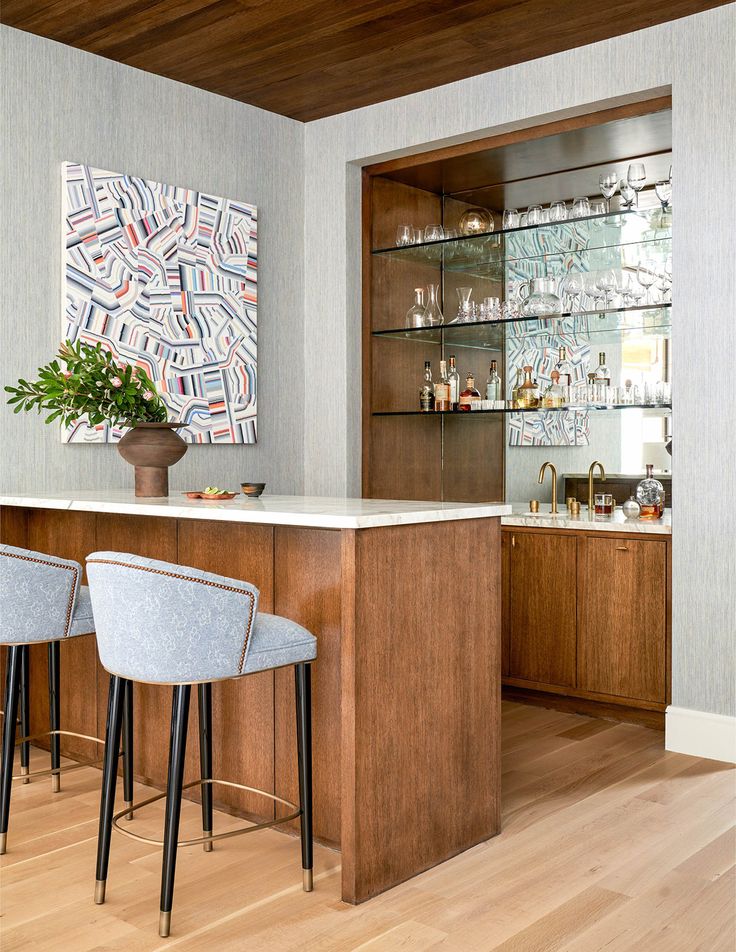 two bar stools sit at the end of a counter in front of a painting