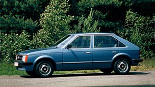 a blue car is parked on the side of the road in front of some trees