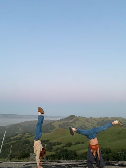 two people doing handstands on top of a mountain