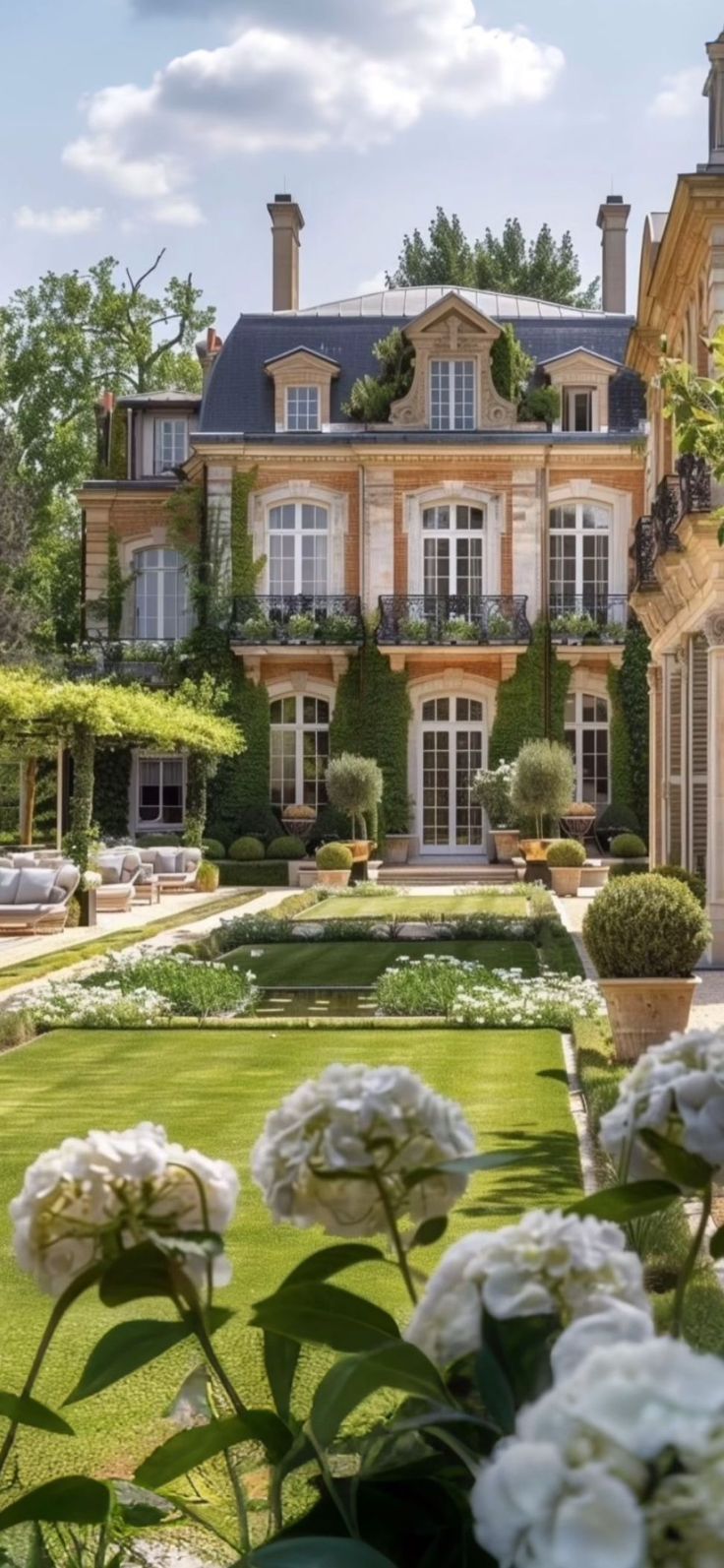 a large house with lots of windows and flowers in the foreground