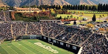 an aerial view of a football stadium with mountains in the background and people on the field