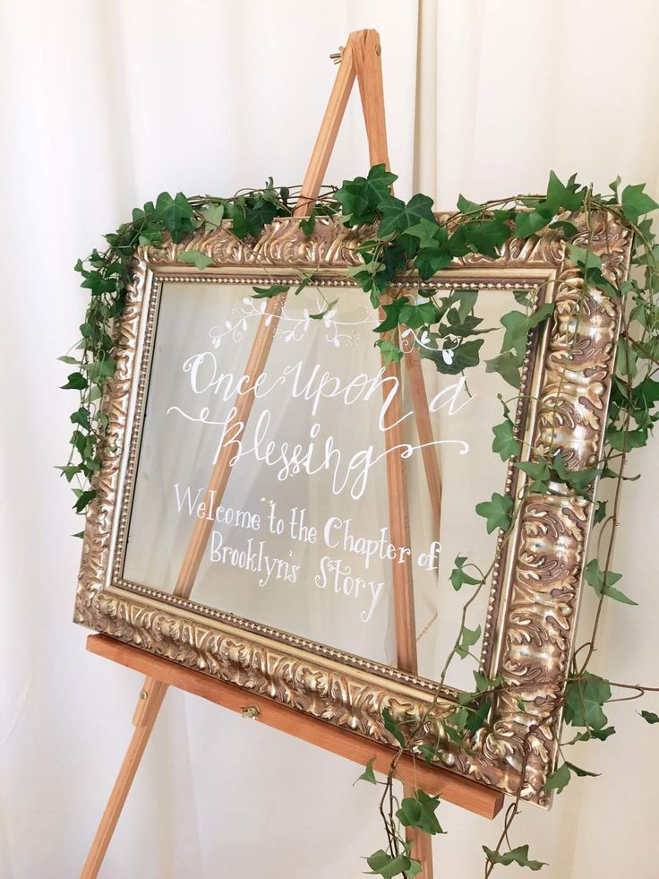 a wooden easel holding a sign with ivy growing on it