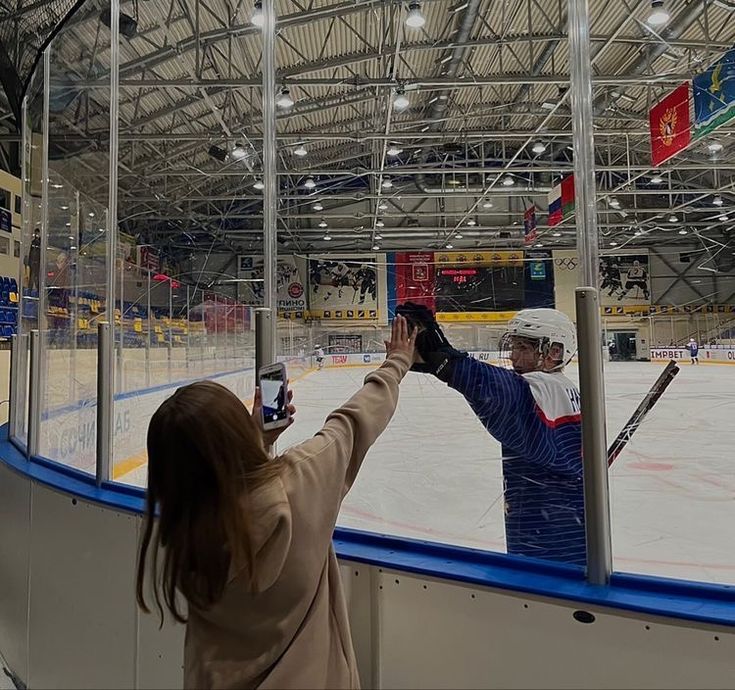 two people taking pictures of an ice hockey rink