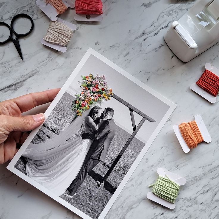 a person holding up an image of a bride and groom in front of some spools of thread