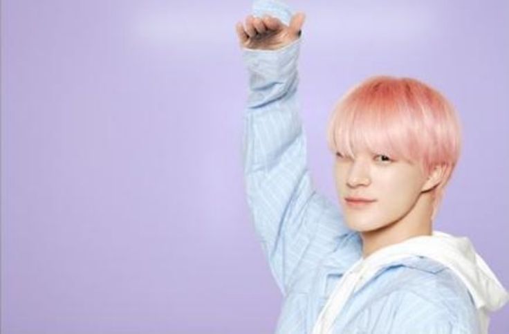 a young man with pink hair raising his hand