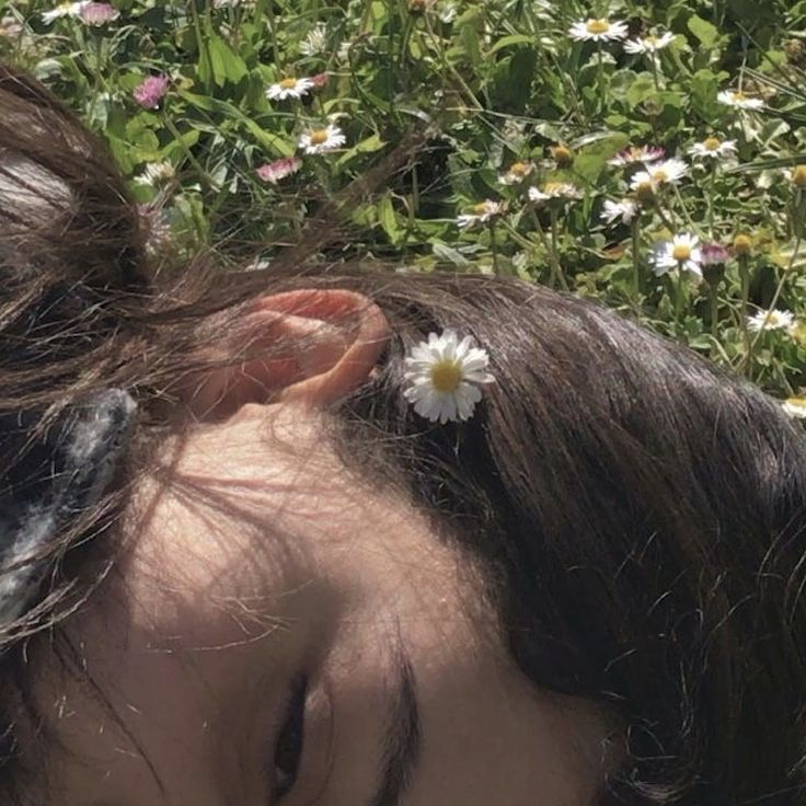 a woman with her hair in the wind and a flower pinned to her ear