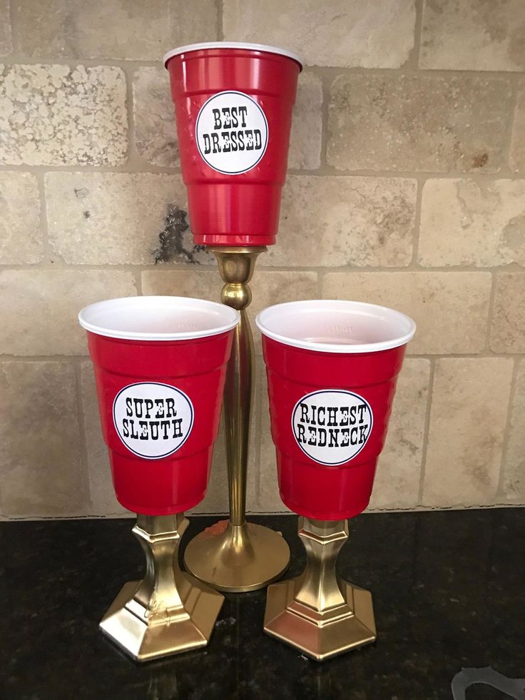 three red cups sitting on top of a gold stand next to a brick wall and floor