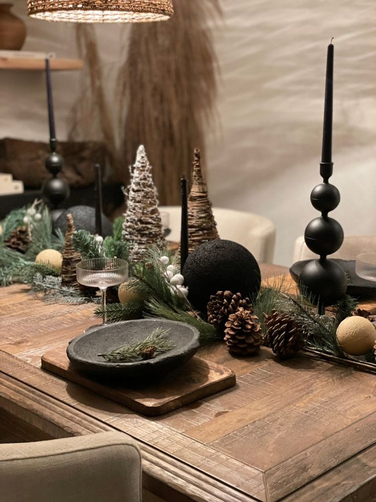 a wooden table topped with lots of christmas decorations next to candles and pineconis