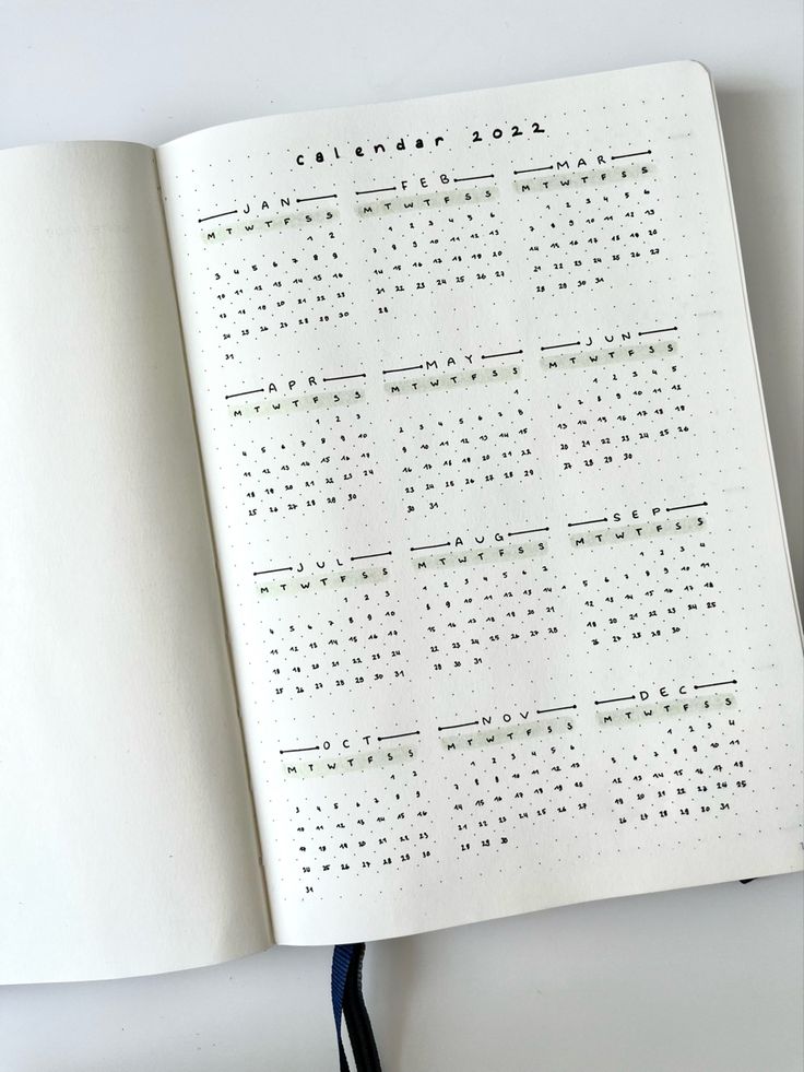 an open notebook with a calendar on the page and a black cord attached to it