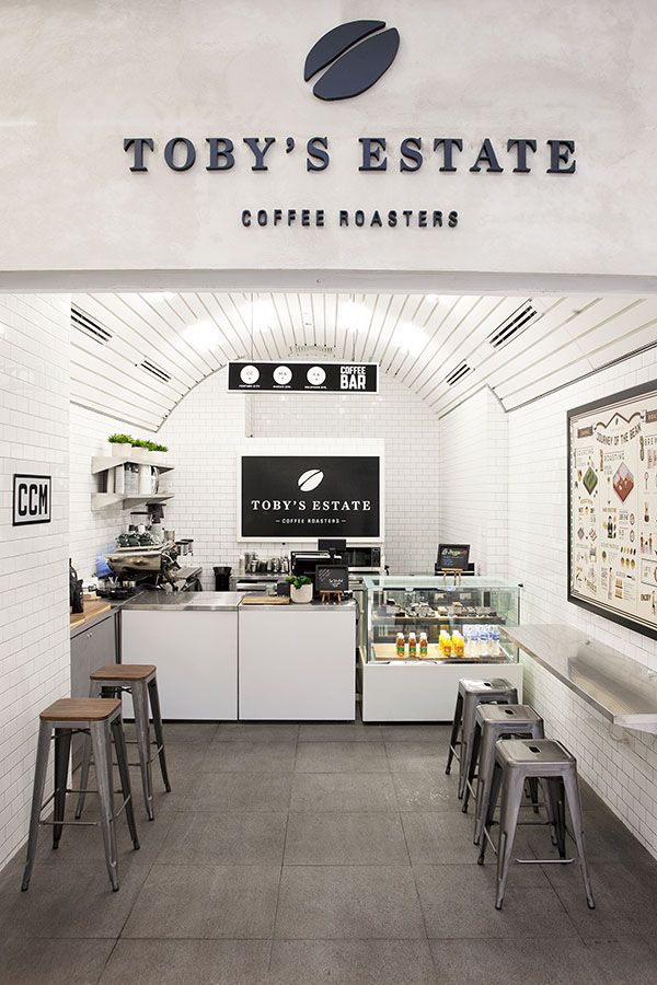 the inside of a coffee shop with stools in front of it and a sign that says toby's estate coffee roasters