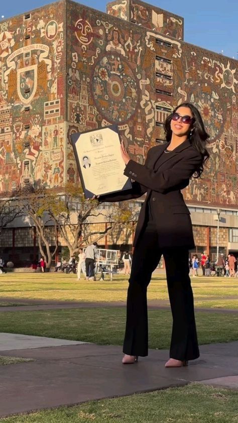 a woman is holding an award in front of a building with many designs on it