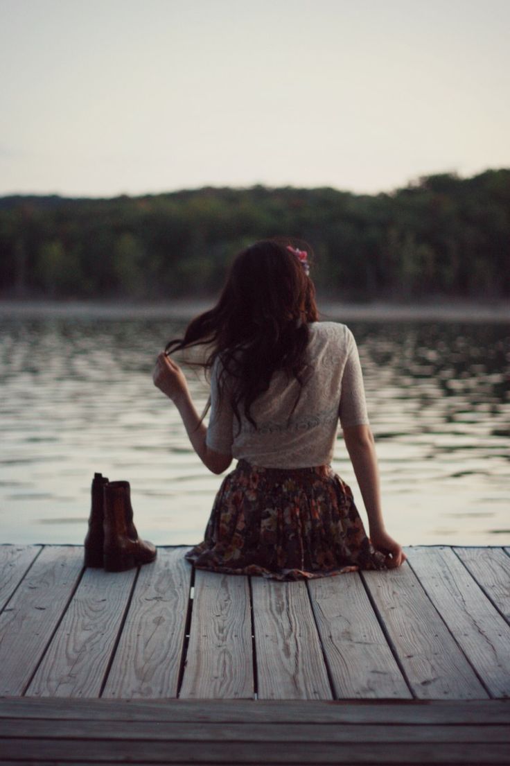 a woman sitting on top of a wooden dock