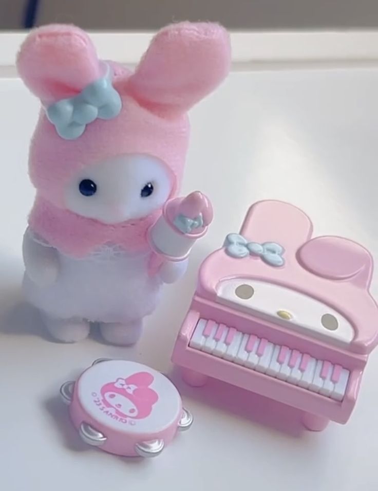 a pink toy with a bow on its head next to a keyboard and key board