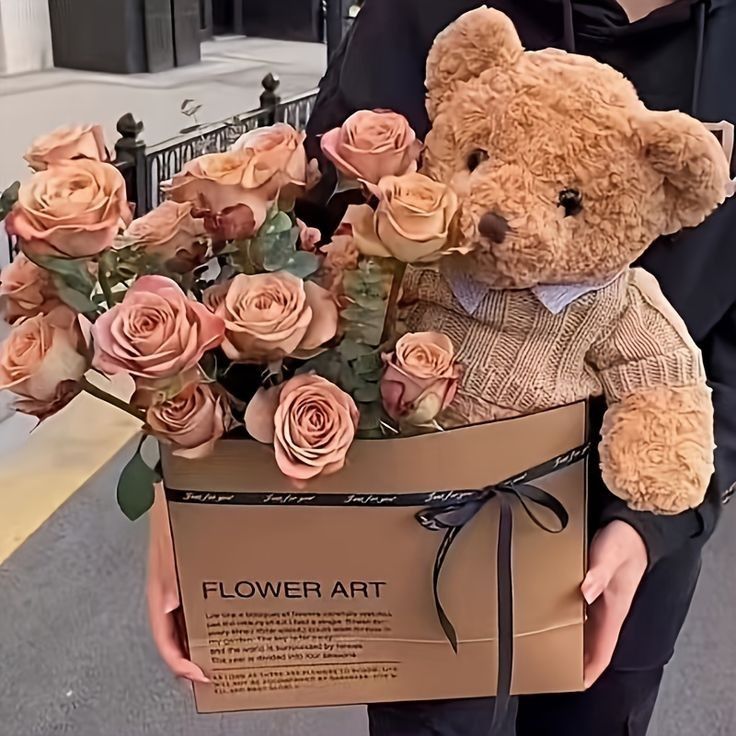 a person holding a teddy bear with roses in it's lap and wearing a sweater