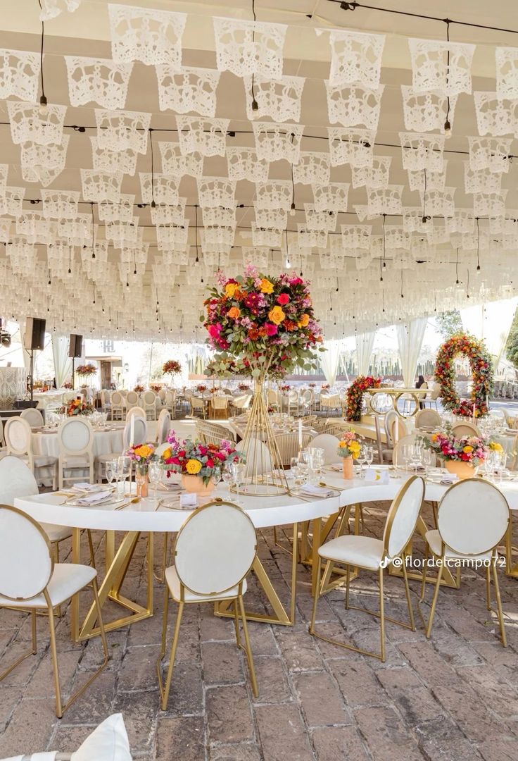 the tables are set up for an event with white linens and floral centerpieces