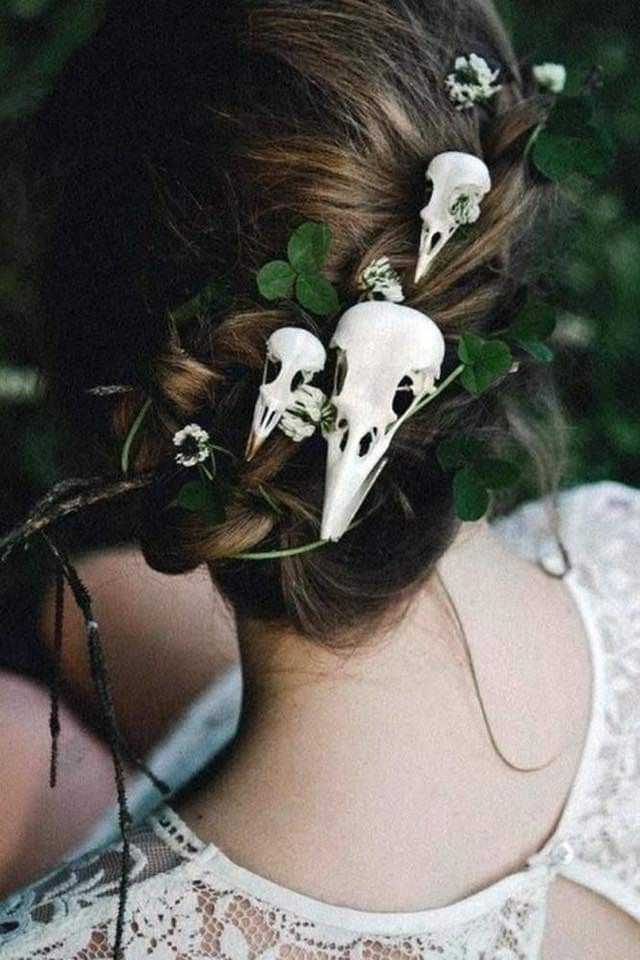 a woman with flowers in her hair and two white skulls on the back of her head