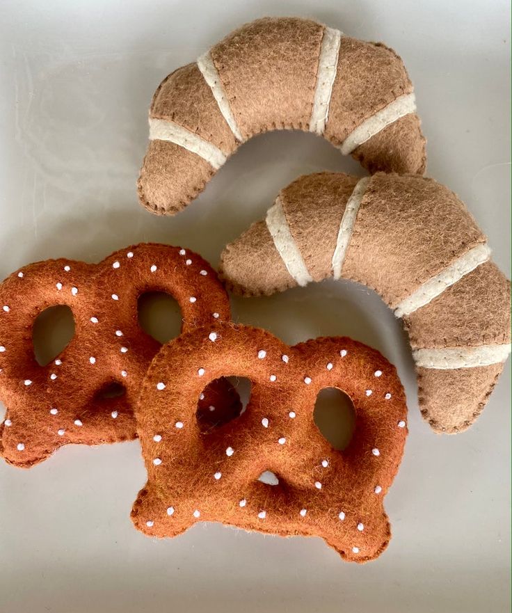 two pretzels are sitting next to each other on a white surface with a brown bagel in the middle