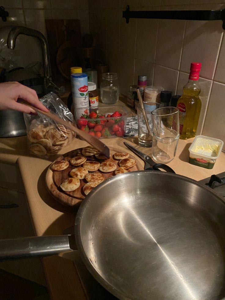 a person cutting up food on top of a kitchen counter next to a bowl and pan