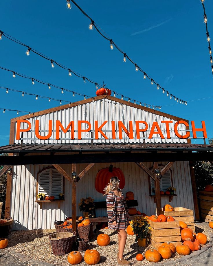 a woman standing in front of a pumpkin patch