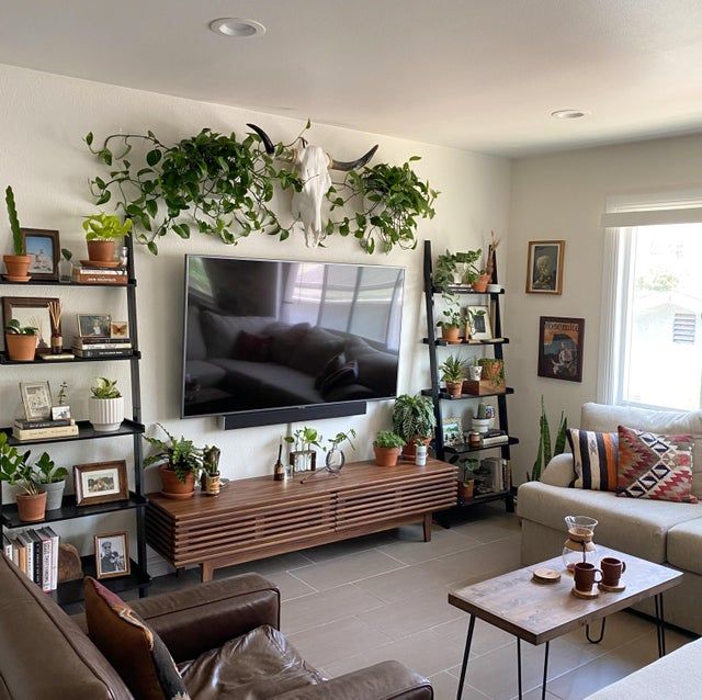 a living room filled with furniture and lots of greenery on the wall above a flat screen tv