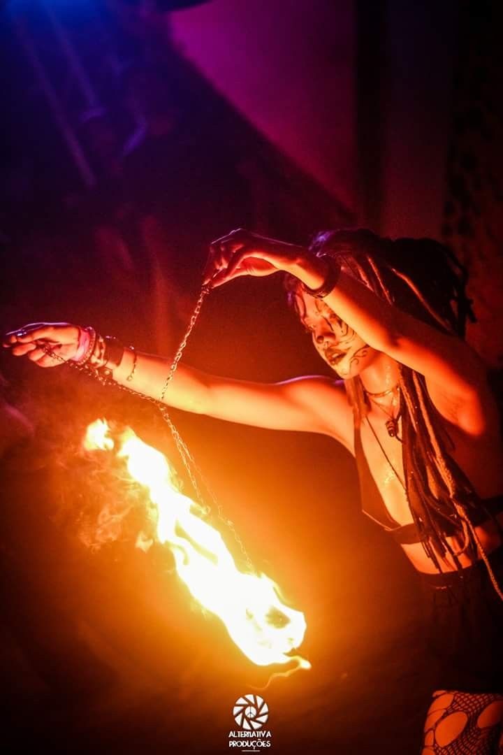 a woman standing in front of a fire with her hands on top of the flame