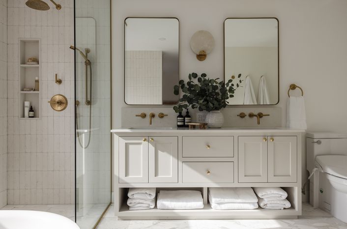 a white bathroom with two mirrors on the wall and a tub in the shower area