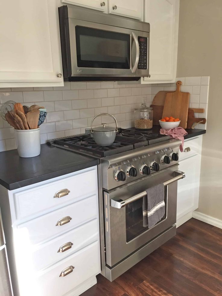 a stove top oven sitting inside of a kitchen next to a microwave and countertop