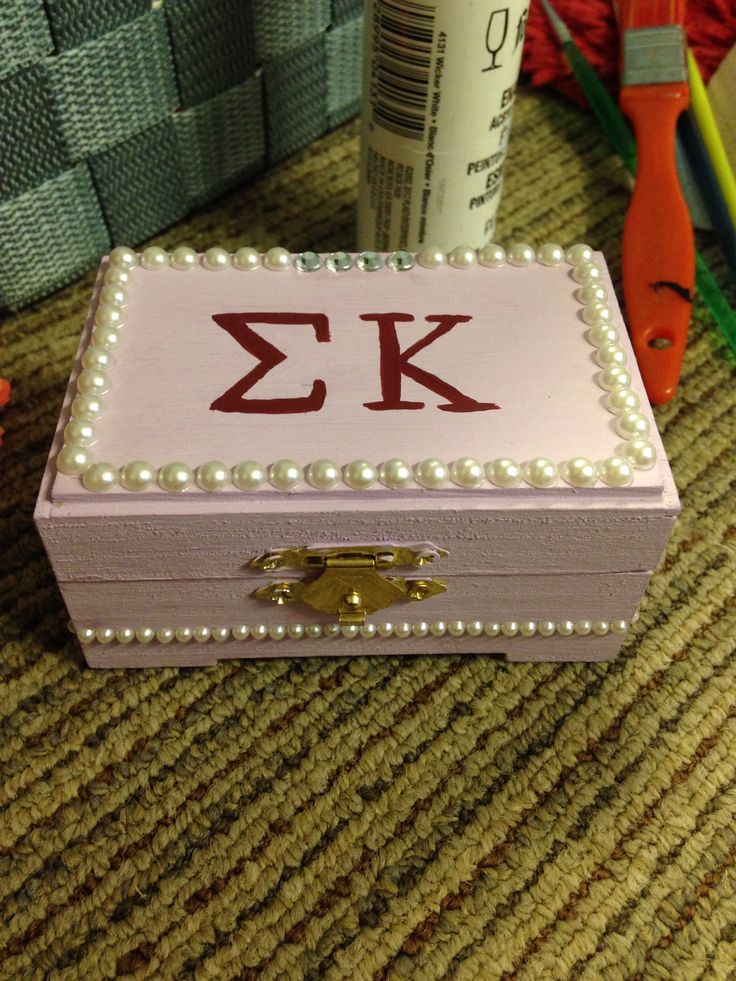 a box with pearls and letters on it sitting next to a pair of scissors, pencils and other crafting supplies