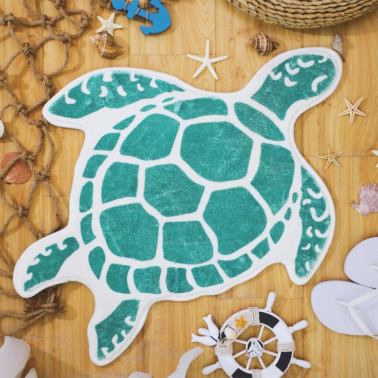 a green turtle rug sitting on top of a wooden floor next to sea shells and starfish