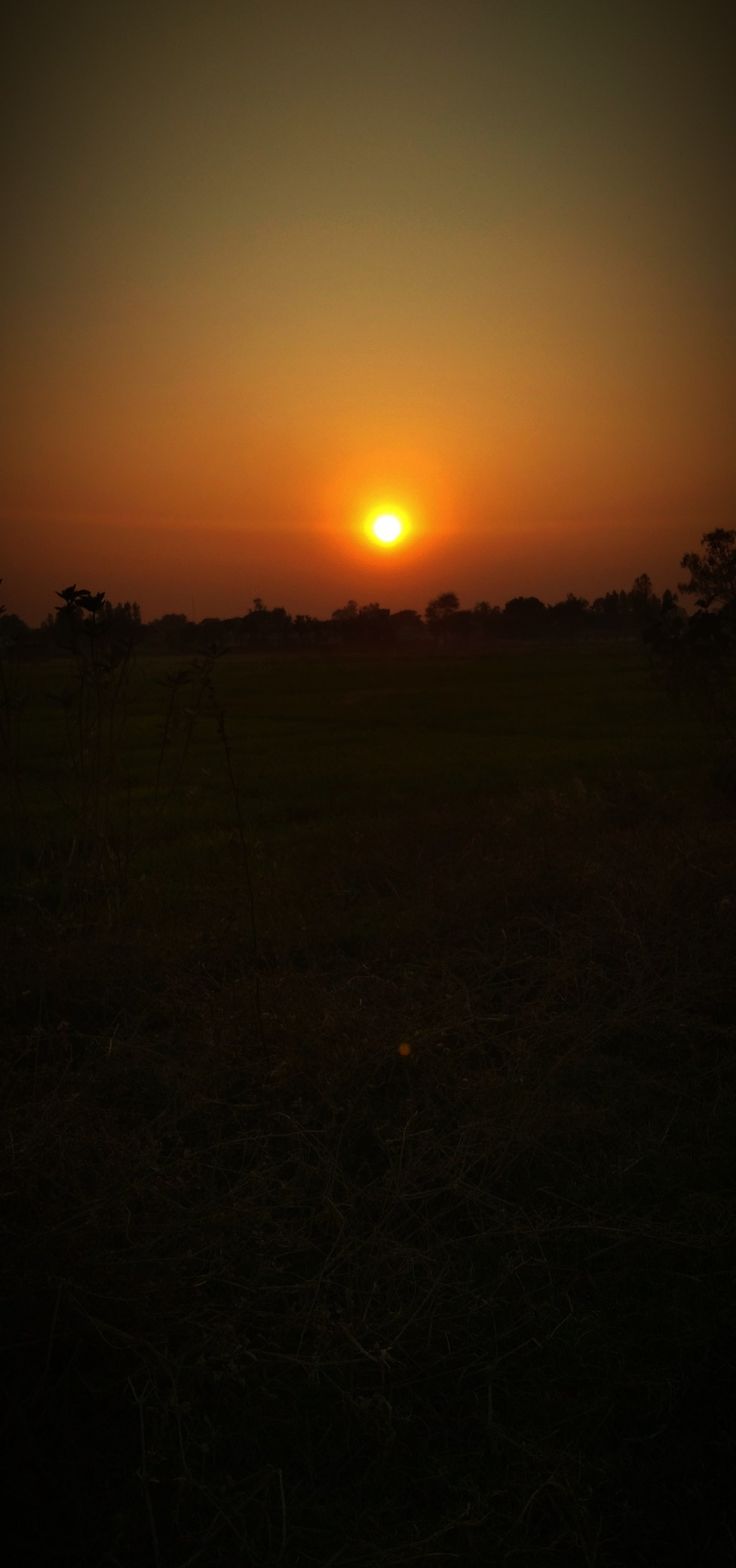 the sun is setting over an open field