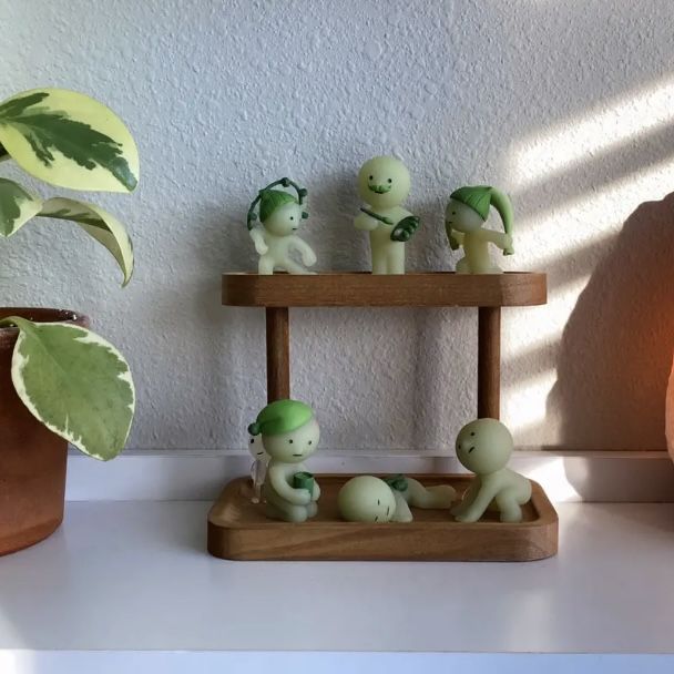 some little figurines sitting on top of a shelf next to a potted plant